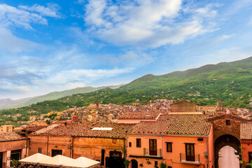 Obraz premium beautiful travel landscape of old european town with ancient church and vintage roofs in mediterranean style with amazing view to great green mountain and nice blue cloudy sky on background