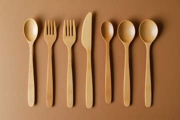 Biodegradable bamboo cutlery set artistically arranged on an earthy-toned background with empty space for text