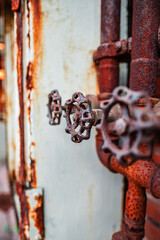 Close-Up Image of Rusty Valve Handles on Industrial Pipes with Textured, Weathered Surfaces in an...