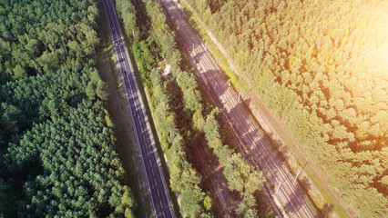 Top-down view of train tracks and highway surrounded by trees