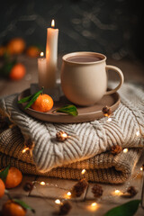 Christmas hot chocolate with tangerines and burning candles on a stack of knitted sweaters creates a cozy winter atmosphere with warm bokeh lights, Mocha Mousse