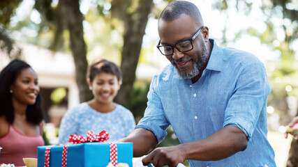 A middle-aged man joyfully cuts into a retirement cake surrounded by friends during a heartfelt celebration.