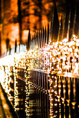 Magical Holiday Night Scene with Glowing Festive Lights Draped Along a Decorative Iron Fence in a...