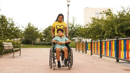 Woman pushing brother in wheelchair on footpath at park