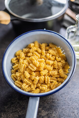 Uncooked italian pasta. Radiatori pasta in colander.