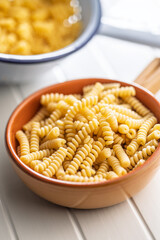 Uncooked italian pasta. Fusilli pasta in bowl on white table.