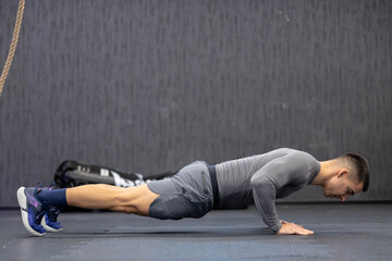 A man executes a perfect push-up on the gym floor with refined technique and concentrated posture,...