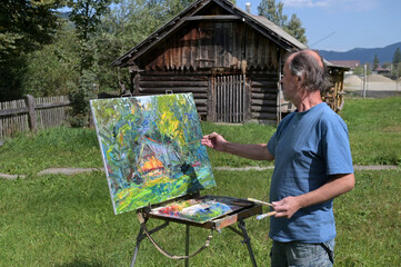 The artist paints a picture on canvas with oil paints.