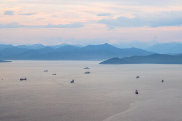 Beautiful evening seascape. Top view of the ships in the roadstead in the bay. Mountains in the distance. Many ships in the sea bay. Avacha Bay, Pacific Ocean. Kamchatka Territory, Far East of Russia.