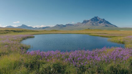 Naklejka premium Serene Mountain Landscape with Tranquil Pond Surrounded by Vibrant Purple Wildflowers Under a Clear Blue Sky in a Remote Natural Setting