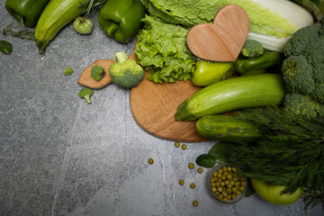 Top view green vegetables and wooden heart on a cutting board