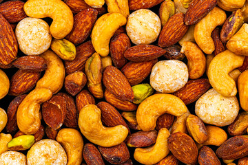 Top view of roasted salted mixed nuts, cashews, almond and macadamia, closeup, background.