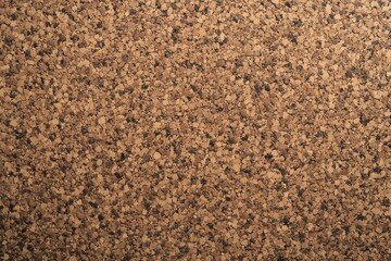 A close-up view of a textured cork surface with a natural brown color and speckled pattern. Ideal for backgrounds, design projects, or environmental concepts.