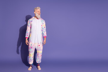 Joyful man wearing a colorful unicorn party costume against a purple background