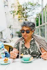 Senior woman enjoying coffee and muffin at outdoor cafe