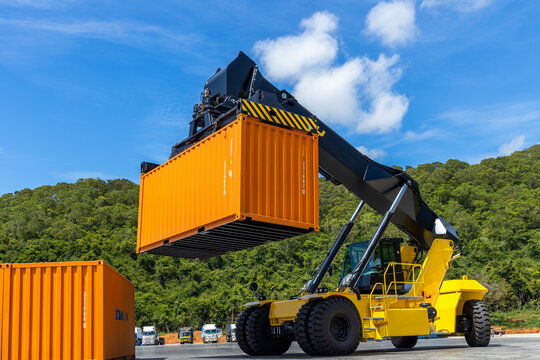 Reach stacker cargo forklift container box import export logistic transportation industrial, Reach stacker pick up container, Reach stacker container loader crane lifting maritime cargo container.
