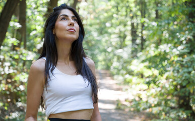 Beautiful  woman relaxing and breathing fresh air with sunlight in the summer park