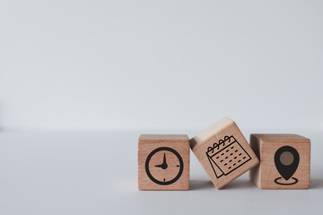 Wooden cubes featuring time, date, and address icons, ideal for concepts like scheduling, event planning, and time management.