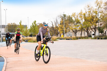 Group of athletic people riding bicycles outdoors, space for text