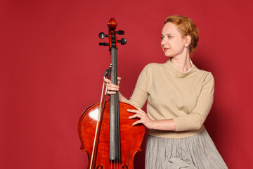 Beautiful young woman with cello on red background © New Africa
