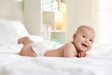 Cute little baby in diaper on bed indoors