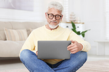 Senior man using laptop on floor at home