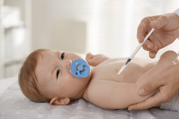 Pediatrician giving injection to cute baby in clinic, closeup