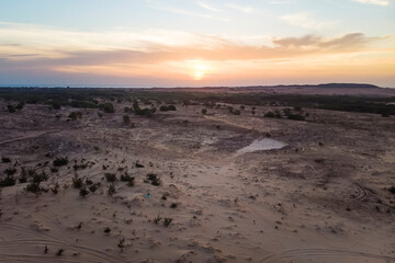 Landscape of sun over skyline in desert at White Sand Dunes Mui Ne, Vietnam. Countryside panorama under scenic colorful sky at sunset dawn sunrise. Beautiful view bright dramatic sky dark ground