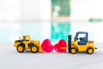 Forklift truck and front loader truck with red heart over blurred background, love industry, outdoor day light, valentine background idea