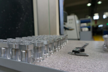 CNC-Machined Metal Parts on Inspection Table and Digital Vernier Caliper. Industrial scene,...