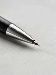 Fototapeta premium A close-up of a pen on a piece of paper. The pen is black and silver and the paper has a subtle dotted pattern.