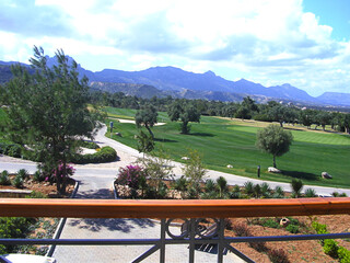Golf course with bunkers in sunny day. Trees surround course. View from above. Outdoor sports activities at country club. Mountains. Gardening