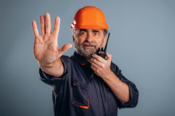 Worker is talking by walkie talkie. Senior man is standing in the studio against background