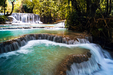 Turquoise water of Kuang Si waterfall, Luang Prabang. Laos. Smooth rocks with cascading water make a series of beautiful short waterfalls in dense forest of National park