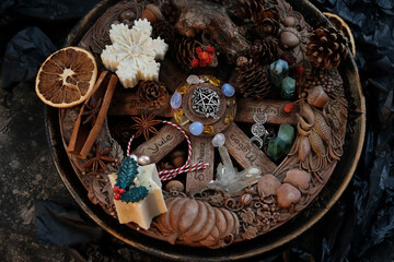 Wiccan altar for Yule holiday. Wheel of the year with amulets, crystals, nuts, cones, decorations on dark table close up. Esoteric Ritual for Yule, Magical Winter Solstice, witchcraft. top view