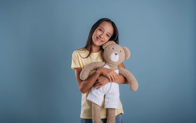 Cute toy in hands, embracing it. Young girl is against background