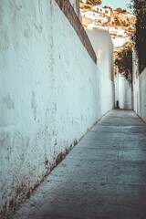 Obraz premium A city street featuring a long concrete wall covered in white plaster, with ample copy space.