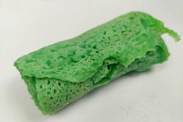 Green rolled pancakes filled with coconut mixed with brown sugar on the table