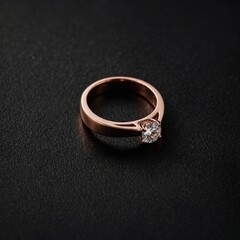 A minimalist rose gold ring lying on a matte black background.
