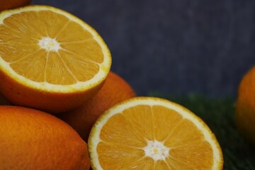 Juicy oranges on green grass, with a stone wall in the background.