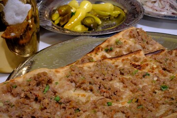 Close-up photo of traditional taste of Turkish cuisine, Konya meat bread, on copper plates. It is served with frothy buttermilk and pickles. Food industry, restaurant food. Types of pita bread.