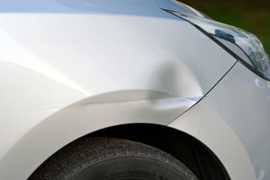 Front fender damage with large dent from an accident, collision repair and auto bodywork challenges. Car with dented front fender from crash impact, vehicle damage need for repair, selective focus