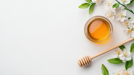 Glass jar of organic honey with wooden dipper and flowers