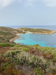 Turquoise bay surrounded by rocky hills and lush vegetation
