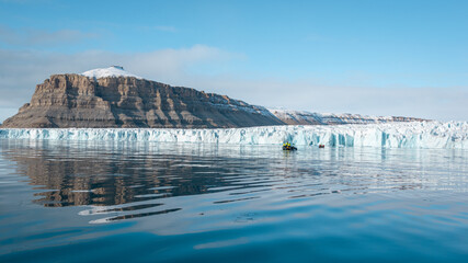 Giant glacier at Crocker Bay on Devon Island, reflection in calm water, sunny day, Canadian Arctic,...