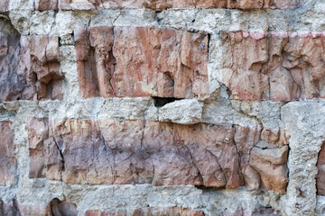 Close-up of a weathered brick wall with visible cracks and rough textures, highlighting the aged and rustic construction.