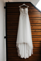 The dress is white with transparent elements on the shoulders and top. The top part of the dress is decorated with lace and has a sleeveless design.