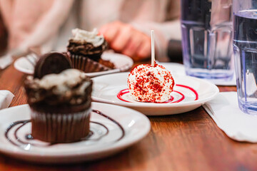 Delicious Dessert Spread Featuring Chocolate Cupcakes and a Red Velvet Cake Pop on a Stylish Tabletop Setting with Elegant Decor at a Cozy Cafe or Bakery