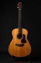 Obraz premium An acoustic guitar is currently sitting on a stand against a black background