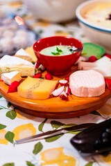 Gourmet Cheese Platter with Various Cheeses and Dips on a Wooden Board Adorned with Radishes and Fresh Parsley for a Delightful Culinary Presentation